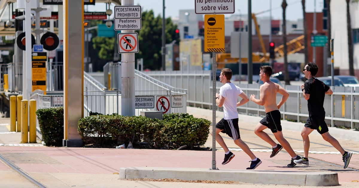 Three men running beside signage